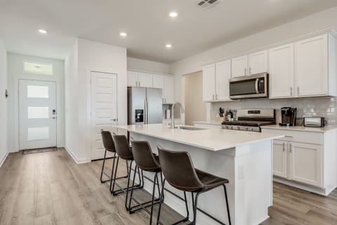 Kitchen features an island with 4 barstools.