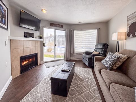 Warm, welcoming living space with fireplace, plush seating, and patio views for cozy relaxation