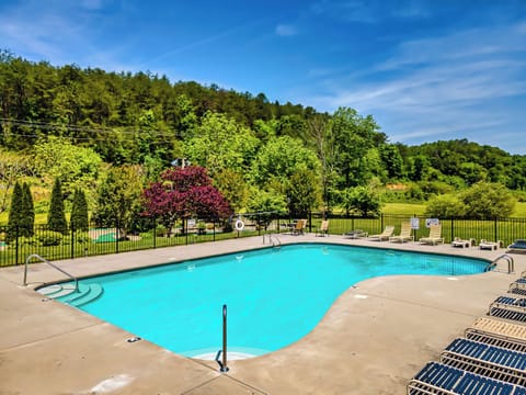 Outdoor resort pool with a cascading waterfall, surrounded by lush greenery.