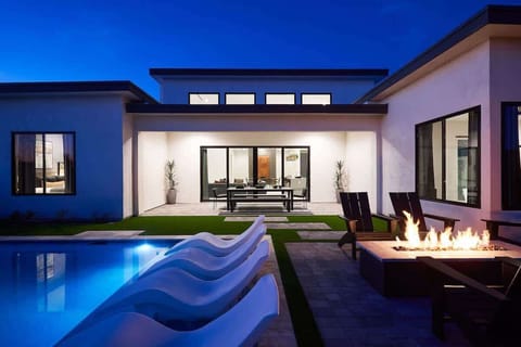 Unit 2: Resort-like backyard with a covered patio offering outdoor dining with seating for 8 guests, a sparkling blue heated pool with sun loungers, BBQ grill and a fire pit.