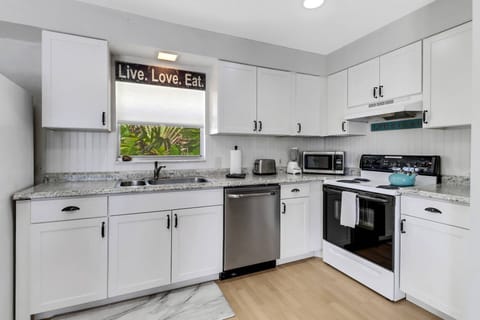 The open kitchen includes a stove, refrigerator/freezer, dishwasher, microwave and pantry cabinet.