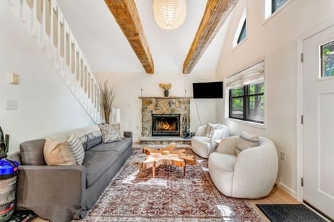Relax in the living room with a comfy couch, a two-seater sofa, a traditional indoor wood fireplace, and a TV.