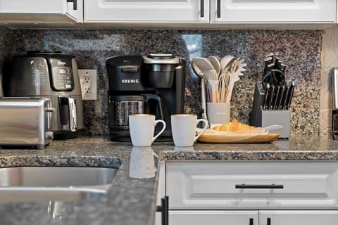 Close-up of kitchen essentials including a dual coffee maker, air fryer, toaster, and a set of knives and utensils.