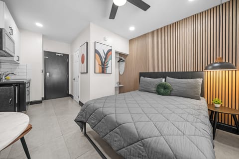 The queen bed is the focal point of this studio, accented by modern, wooden wall paneling and soft linens. It provides a comfortable resting place after a day of exploring.
