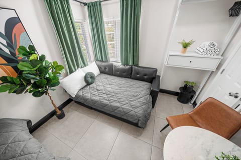 This studio offers flexibility with a cozy leather sofa bed for additional sleeping. Surrounded by natural light from corner windows and lush greenery, the space provides a serene, comfortable area to relax after a day of exploring South Beach.
