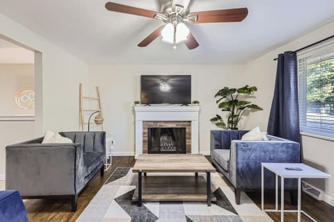 Living room with fireplace, ceiling fan, and plush couches