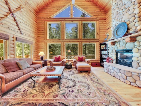 Spacious living room featuring a stunning floor-to-ceiling gas fireplace and expansive forest views