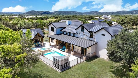 An aerial view showcases this luxurious Hill Country property with a pool, hot tub, and lush greenery.