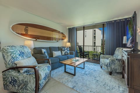 Relax in your tropical-inspired living room where coastal charm meets comfort—complete with surfboard art and ocean breezes from your private balcony.