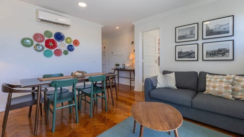A comfy living room with a sofa, a cable TV, a dining area for 6 people, and balcony access. #lisbon #decoration #home #airbnb #portugal