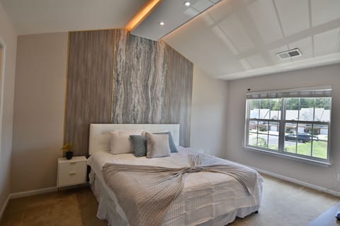 Master bedroom with marble accent wall, natural light, and cozy modern decor