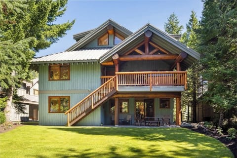 - Rear view of the cabin with spacious deck and green lawn  
- Surrounded by forest trees offering peace and privacy  
- Perfect setting for outdoor dining and morning coffee  
