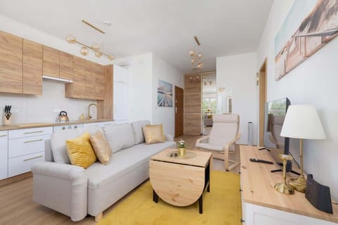 A beautifully lit living room with modern Scandinavian-style decor, featuring a beige sofa, natural wood finishes, and yellow accents that create a warm and inviting atmosphere.