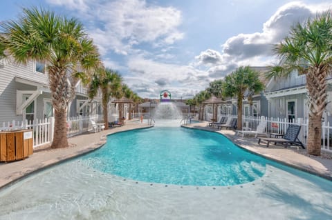 Dive into your tropical oasis! Crystal-clear pool waters await surrounded by swaying palms and charming cottages for the perfect beach getaway.