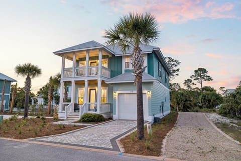 Charming coastal home with palm trees and wraparound porches captures the essence of beachside living.