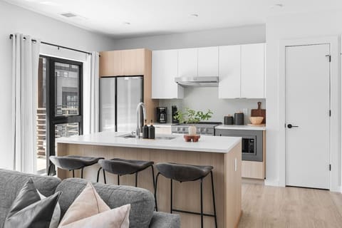 Fully equipped kitchen with high-end appliances and finishes, plus seating for three at the counter.