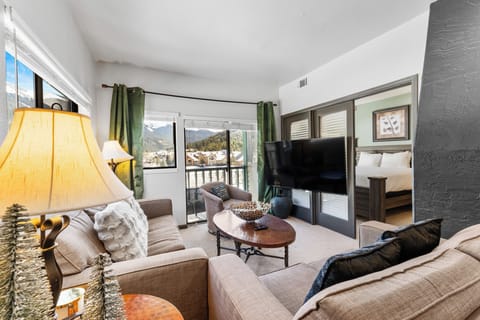 Unwind in your cozy living room with plush seating and stunning mountain views through floor-to-ceiling windows.