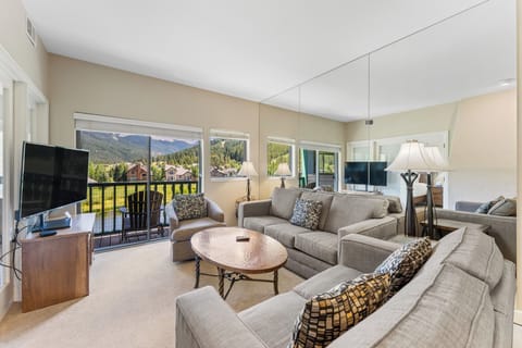 Relax in your spacious living room with plush sectional seating and stunning mountain views through floor-to-ceiling windows.