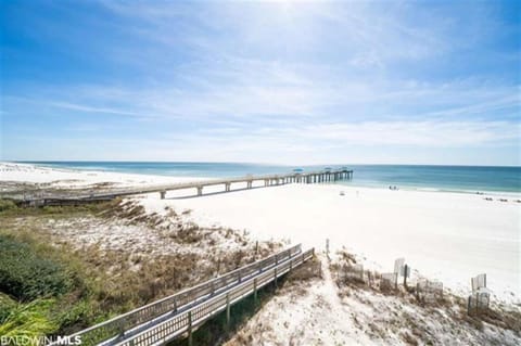 A stunning view from the condo overlooking the white sandy beach and the sparkling waters of the Gulf of Mexico, stretching eastward into the horizon.