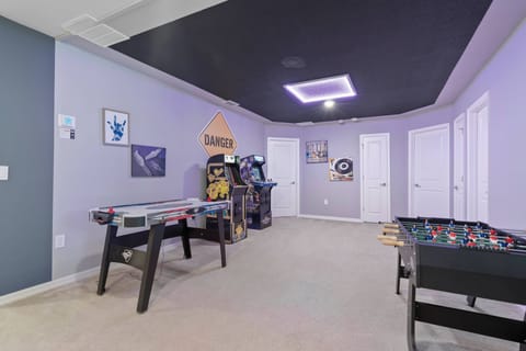 Enjoy a vibrant game room with a sleek air hockey table and foosball table, perfect for friendly matches. The playful decor and soft carpet create a fun atmosphere, inviting you to relax and enjoy lively entertainment.