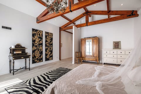 Master bedroom decorated with a large chandelier, an antique desk and zebra rug