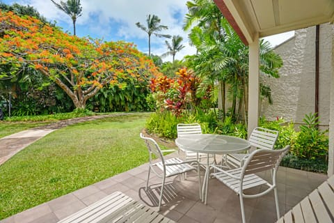 Your private patio overlooks a lush tropical garden with vibrant flowering trees and swaying palms, perfect for morning coffee or quiet relaxation in the warm island breeze.