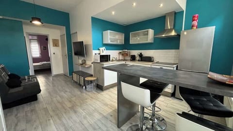 Cuisine ouverte sur le salon, équipée avec four, plaques de cuisson, bouilloire, machine à café, micro-ondes, grille-pain et réfrigérateur avec congélateur.
Coin repas pour quatre personnes.