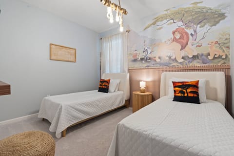 This playful bedroom offers two cozy twin beds adorned with vibrant animal-themed pillows, creating a fun atmosphere for guests of all ages. A delightful wildlife mural and abundant natural light enhance the cheerful vibe.