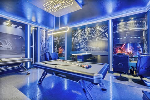 Discover a lively game room with vibrant blue lighting that creates a fun atmosphere. Enjoy a sleek pool table and unique wall art, making it an ideal spot for friendly competitions and gatherings with friends.