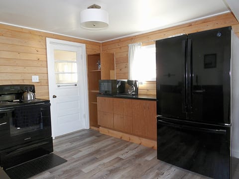 Entry door into the kitchen including microwave, coffee maker, full size fridge