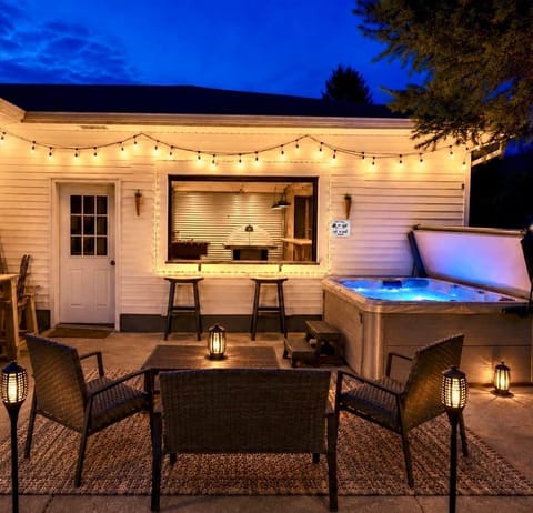 Private patio with hot tub, grill, glowing lights, and indoor/outdoor entertaining space.