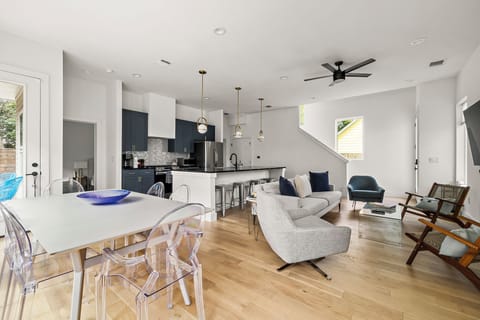 This dining area features a contemporary white square table surrounded by six transparent chairs, creating a sleek and airy look.