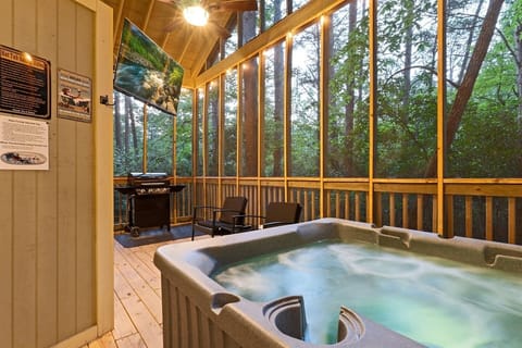Sink into the private hot tub the minute you arrive, screened from the bugs and open to the woods. Movie glowing on the outdoor TV, grill ready, the only sound the trees - this is the porch you won't want to leave.