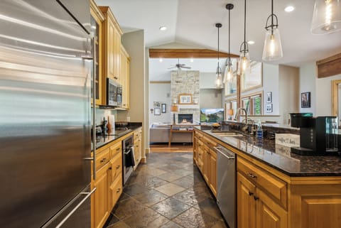 - Modern kitchen with granite countertops and stainless appliances  
- Pendant lighting over bar seating for casual meals and drinks  
- Opens into living room with stone fireplace and cozy sofa