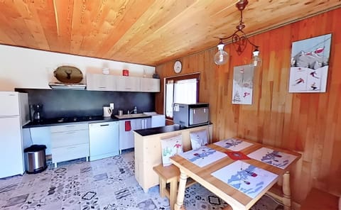 The open plan kitchen and dining area is filled with natural light, featuring wood paneling and a charming tiled floor. The kitchen boasts modern appliances, including a dishwasher, while the dining table is perfect for enjoying meals with a view of the b