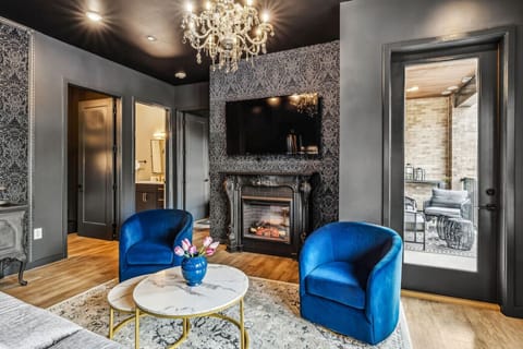 Enjoy a modern, open-plan living space with vibrant blue furniture, a dark blue sofa, and a stylish kitchen with stainless steel appliances and pendant lighting. A chandelier adds elegance to the cohesive design.