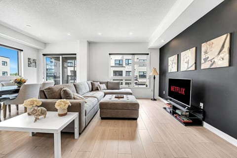 Welcome to your urban sanctuary! This bright, open-concept living room is centered around a plush, oversized sectional sofa designed for ultimate relaxation. Whether you are catching up on your favorite Netflix series on the large flatscreen or enjoying a