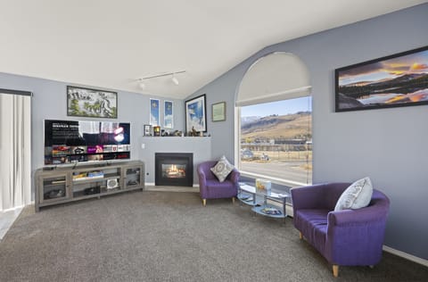 Bright living room with fireplace, large windows, and cozy seating.