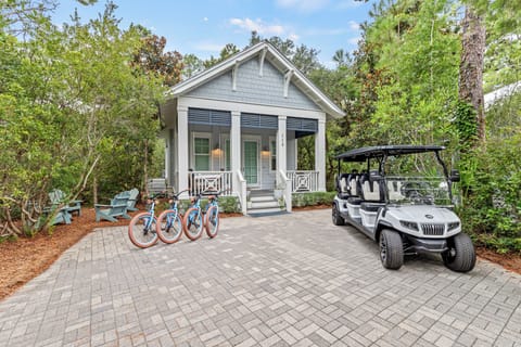 Charming cottage nestled among trees with bikes and golf cart ready for exploring the scenic surroundings.