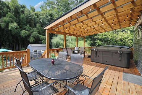 Back deck overlooking the backyard with hot tub, dining area and night time lighting