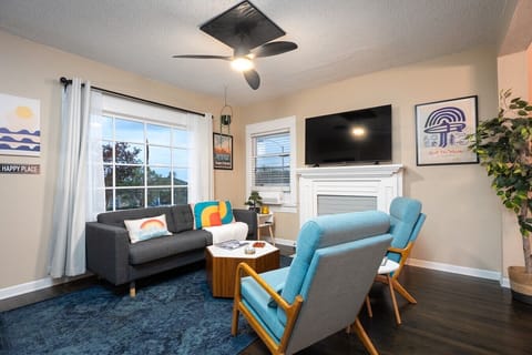 Living room space with comfortable seating, 58` smart TV, AC, ceiling, electric candles, and books