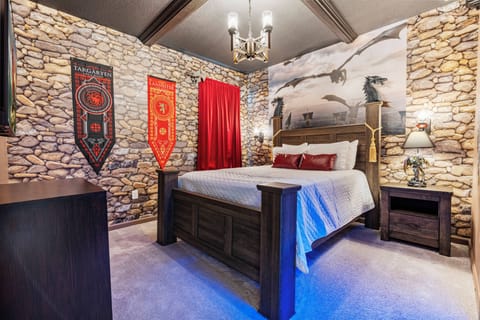 Unwind in our themed bedroom, featuring rich textures, a stunning stone wall, and ornate banners that create a cozy atmosphere with plush carpet and soft lighting—perfect for relaxing after your adventurous explorations.