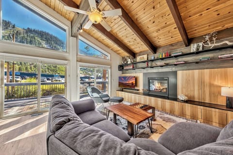 Your cozy living room features exposed beam ceilings, a crackling fireplace, and mountain views through expansive windows.