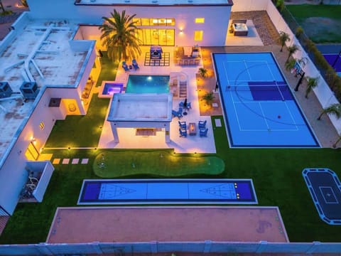 Aerial view of a luxury vacation rental featuring multiple sports courts, a sparkling swimming pool with hot tub, and spacious outdoor entertainment areas perfect for groups.
