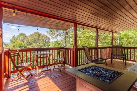 Covered front deck with rocking chairs and outdoor seating overlooking the Smoky Mountain landscape near Bryson City. The elevated porch provides a scenic space to relax and enjoy long-range mountain views.