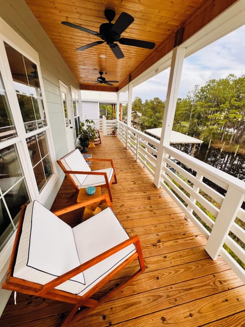 Covered balcony with waterfront view, comfortable seating and ceiling fans. 