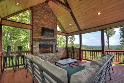 Main level porch with sitting area, small bar, tv and fireplace 
