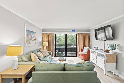 A bright and inviting living room with cozy seating and a TV for comfort.