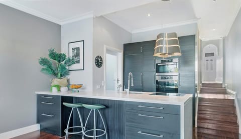 A sleek, modern kitchen featuring dark cabinetry and a central island with bar seating.