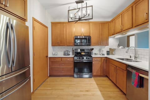 Cook your favorite meals in this fully equipped kitchen featuring warm wood cabinetry, stainless steel appliances, and elegant subway tile backsplash.